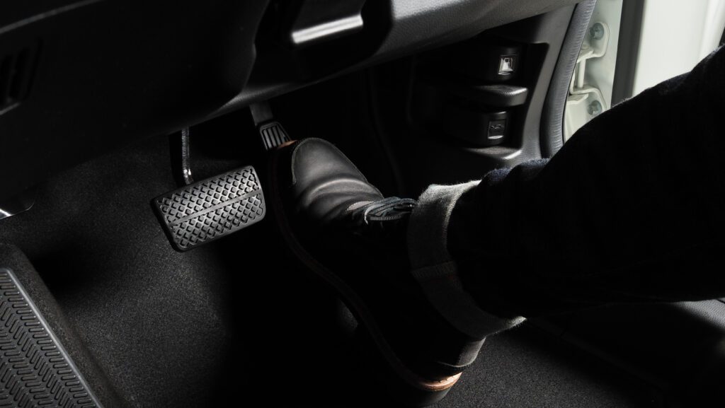Close up the foot pressing foot pedal of a car to drive, using the accelerator and brake pedal in a car.