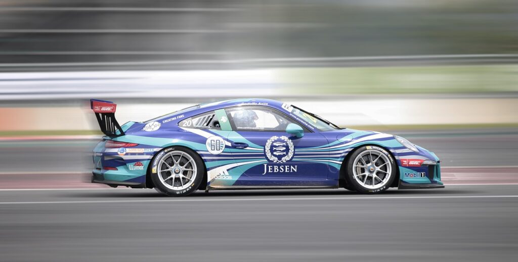 A blue race car is speeding on a track practicing throttle application.