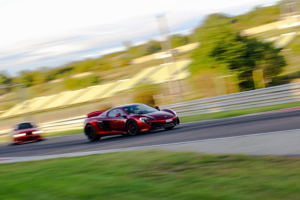 Red sports car driving fast on a racetrack.